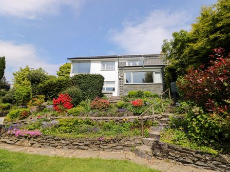 A house with stone terraces and stairs surrounded by various plants and flowers at Briars Lea in Bowness-On-Windermere
