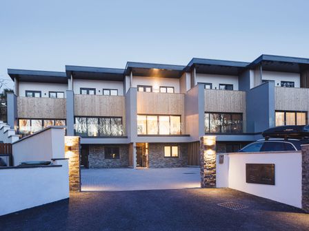 A modern multi-unit residential building with stone pillars and illuminated entrance at 3 Ocean Walk in Perranporth