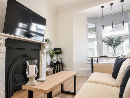 A living room with a sofa coffee table and television above a fireplace at Fore Street House - Apartment 2 in Seaton