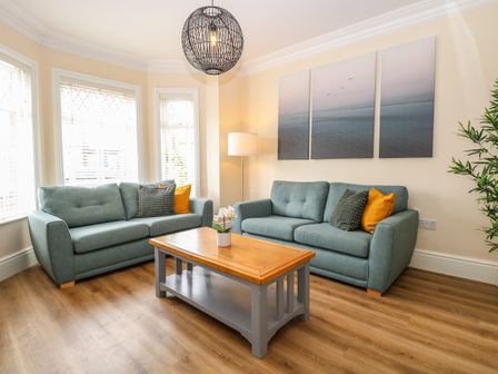 A living room with two sofas a wooden coffee table and a floor lamp at Seaside House in Gorleston-On-Sea
