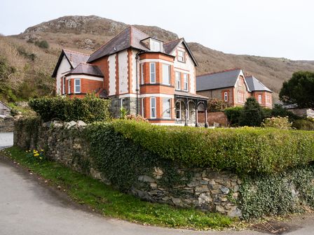 A residential house with a garden surrounded by a stone wall and hedges near hills at Haulfryn in Barmouth