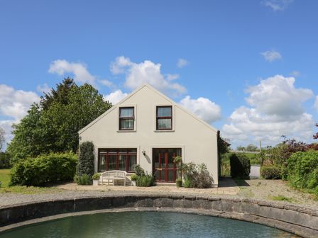 A house with a pond in front and greenery around at The Clove in Poyston Cross near Haverfordwest