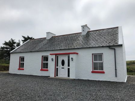 A single-story white house with red window frames and a gravel driveway at Shannagh in New Ross County Wexford