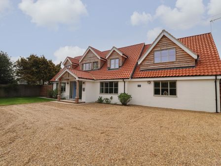 A house with a tiled roof and gravel driveway with some bushes in front at Little Chapter in Walberswick