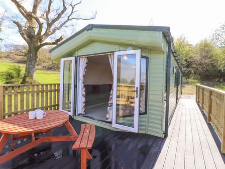 An outdoor deck with a wooden picnic table and open glass doors leading into a room with a sofa at Swinside in Lorton