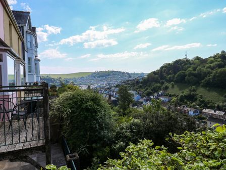 View of houses and hills from a balcony with chairs and railing at High Mount in Dartmouth
