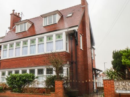 A brick residential house with white framed windows and a red tiled roof at South Bay Beach House in Bridlington