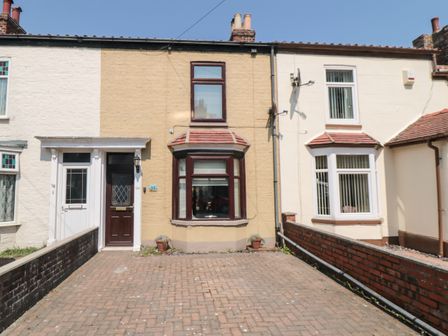 A brick driveway leading to two adjoining houses with bay windows and brown and white doors at Harbour Cottage in Bridlington