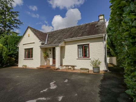 A white house with a sloped roof and tiled steps surrounded by greenery at Brantfell Lodge in Bowness-On-Windermere