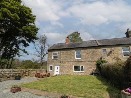 A stone house with a grassy yard and outdoor wooden table and chairs at The Hollow in West Woodburn