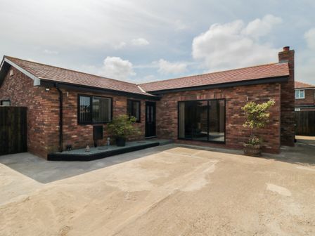 A single story brick house with a driveway and potted plants at 31A The Green in Scalby