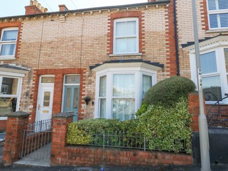 Exterior view of a brick terraced house with blue door white window and small hedge at Leo's Place in Weymouth