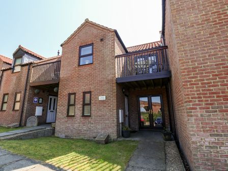 A brick house with balconies a small lawn and paved path at Anstis Cottage in Whitby