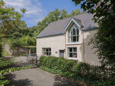 A house with multiple windows surrounded by trees and bushes at The Old Rectory Coach House in Rathmullan County Donegal