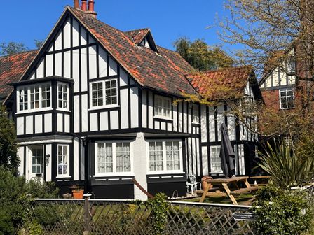 A black and white Tudor-style house with a tiled roof a picnic table garden and trees at 6 The Whinlands Thorpeness