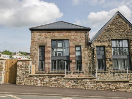 Stone building with large windows and a wooden gate in front at The Old School in Ruspidge