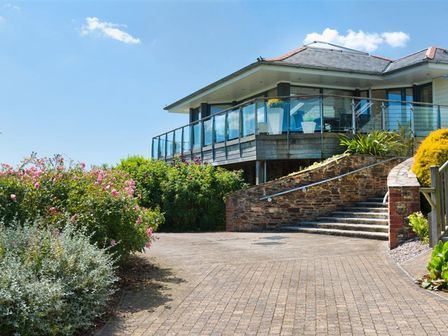 A building with a glass balcony and stairs surrounded by plants and flowers at Vantage Point Hillfield Village Dartmouth