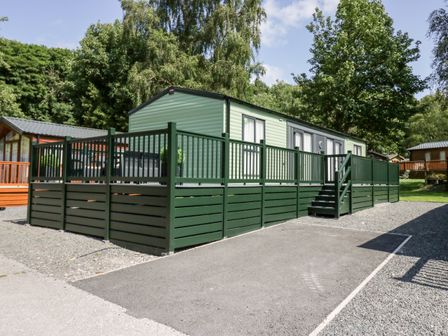 A mobile home with green railing and steps surrounded by trees at 43 Pony Meadow in Troutbeck Bridge