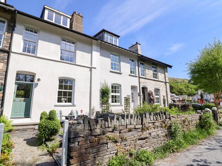 A row of houses with stone fence and garden in front on a sunny day at Glan yr Afon in Abergynolwyn near Tywyn