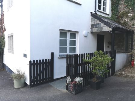 A white house exterior with black wooden fences and gates and several potted plants at Lower Culvermead in Chaddlehanger near Tavistock