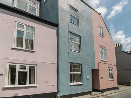 A narrow street with pastel-colored houses including pink and blue at Teal House in Lyme Regis