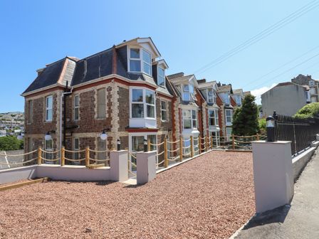 A row of brick houses with white framed windows and a gravel yard at Bradley House in Ilfracombe