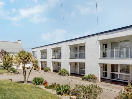 A white two-story building with balconies and plants in front at Westward 14 in Polzeath