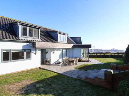 A house with a tiled roof and outdoor patio furniture on the lawn at Pebbles in Southwold