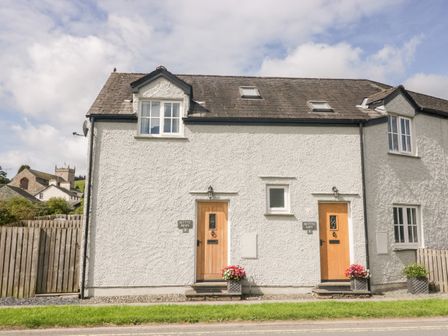 A white two-story building with two wooden front doors and flower pots by the doors at Betty's Loft in Hawkshead