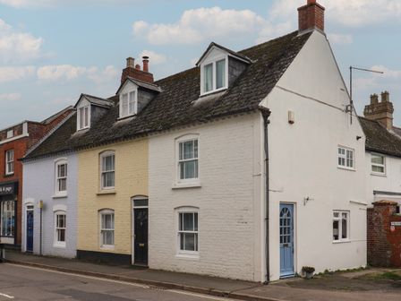 A row of terraced houses with different colored doors and upper windows at Braiders Rest in Bridport