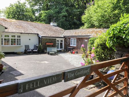 A courtyard with a wooden gate flowers and benches at Fell View The Courtyard in Clappersgate near Ambleside