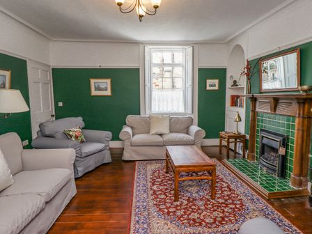 A living room with sofas coffee table fireplace and a patterned rug at Victoria House in Alnwick