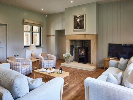 A living room with armchairs sofas a fireplace and a television at The Foal in Humshaugh