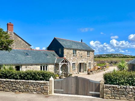 Stone houses with slate roofs and wooden gate in front at The Riblows Cape Cornwall in Bollowal near St Just