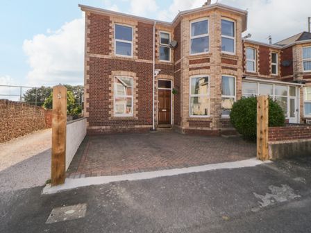 A brick house with bay windows and a paved driveway at 5 Stafford Road in Paignton
