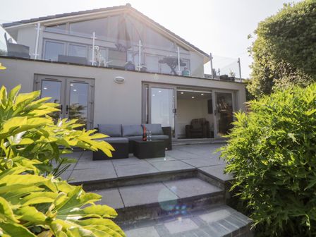 A patio with outdoor seating and glass doors leading inside at Riverview @ 1 Brunel View in Saltash