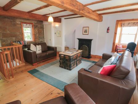 A living room with leather sofas wooden beams a fireplace and a wooden chest coffee table at Bramble Corner Cottage in Staithes