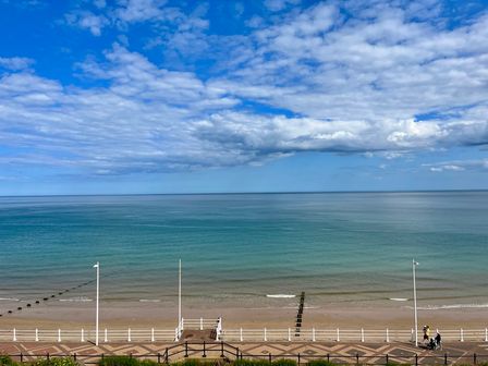 A beach with a promenade and a railing by the sea under a partly cloudy sky at Apartment 9 Beaconsfield House in Bridlington