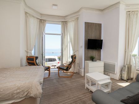 A bedroom with two chairs near a window and a small table in front of a TV at 2 Beach View Beaconsfield House Bridlington