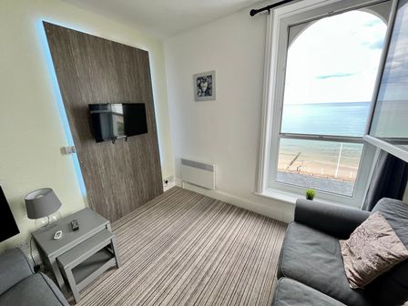 A living room with a wall-mounted tv gray sofas and a window showing a sea view at 7 Beach View Beaconsfield House in Bridlington
