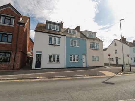 A row of attached houses with multiple windows and doors along a street at Quay Cottage Sea View in Poole
