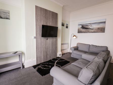 A living room with two gray sofas a wall-mounted television and a floor lamp at Promenade in Bridlington