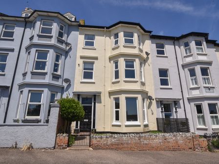 A row of three-story terraced houses with bay windows and small front gardens at Flat 2 10 Seafield Road in Seaton