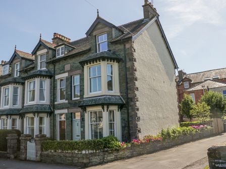 A row of stone and brick houses with bay windows and a small garden with flowers at Heatherlea in Keswick