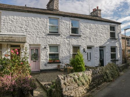 A row of white stone cottages with numbered doors and small front gardens along a street at Gosling Cottage in Kendal