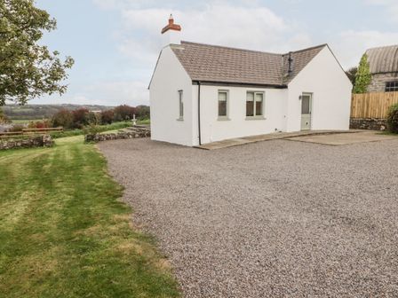 A white house with a gravel driveway and grass lawn at Fountain Folly Moylgrove near St Dogmaels