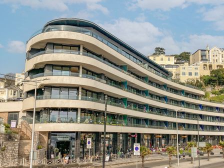 A multi-story modern building with curved balconies and ground floor shops at Apartment 20 Summer Place in Torquay