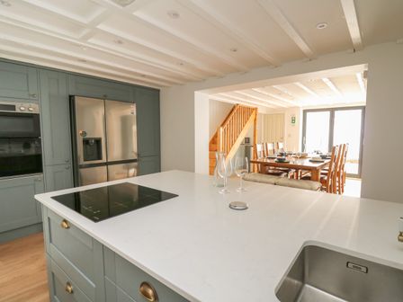 A kitchen with a white countertop island an induction cooktop stainless steel refrigerator and a dining table with chairs at Osborne House in Rhayader