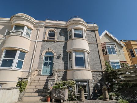 Exterior front view of a stone and stucco house with steps leading to blue front door at 49 Esplanade in Burnham-On-Sea