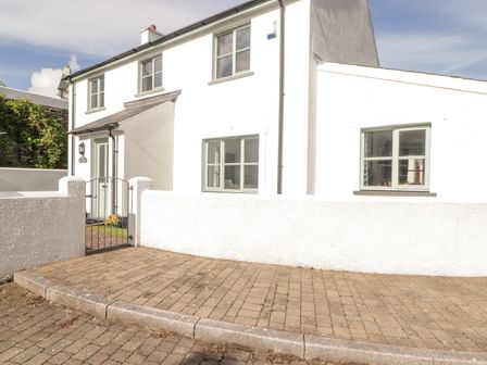 The exterior of a white two-story house with green window frames and a gated entrance at 3 Strawberry Close in Little Haven near Broad Haven